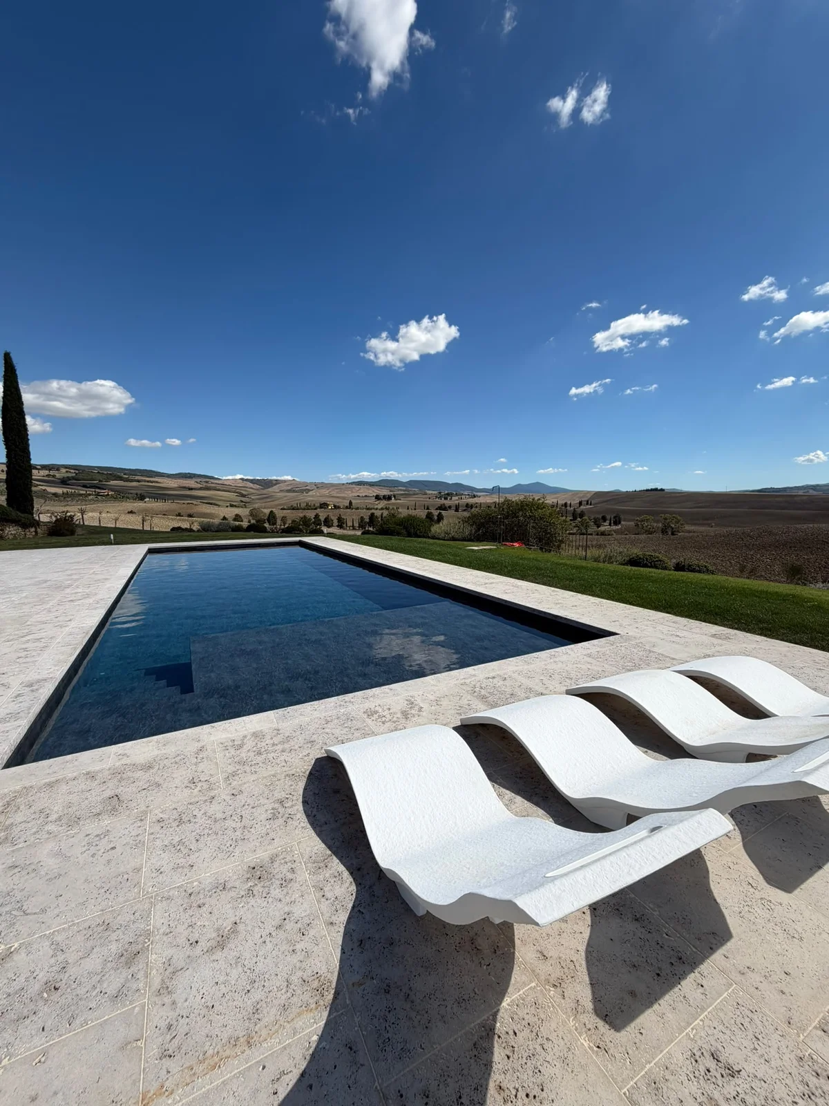 Piscina realizzata da 3A Piscine con bordo in travertino e vista sulle colline toscane